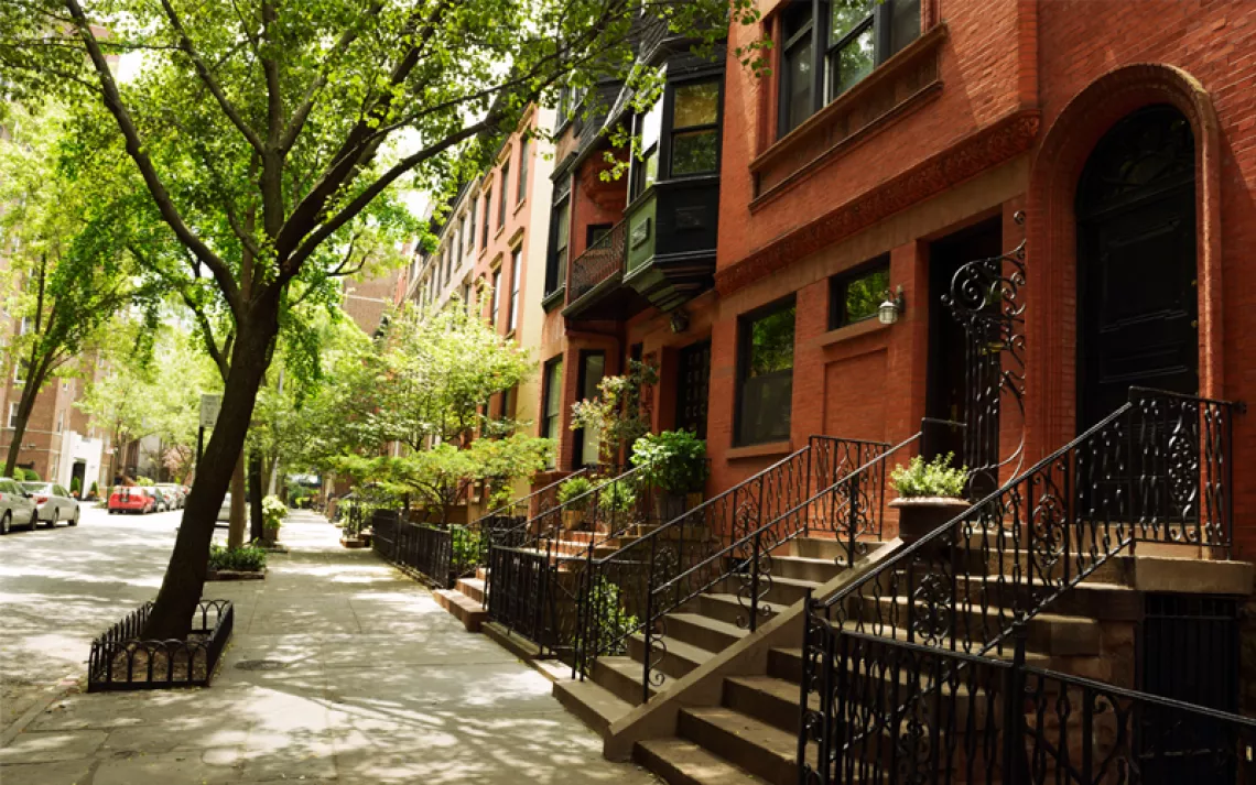 A row of brownstone homes with trees planted out front