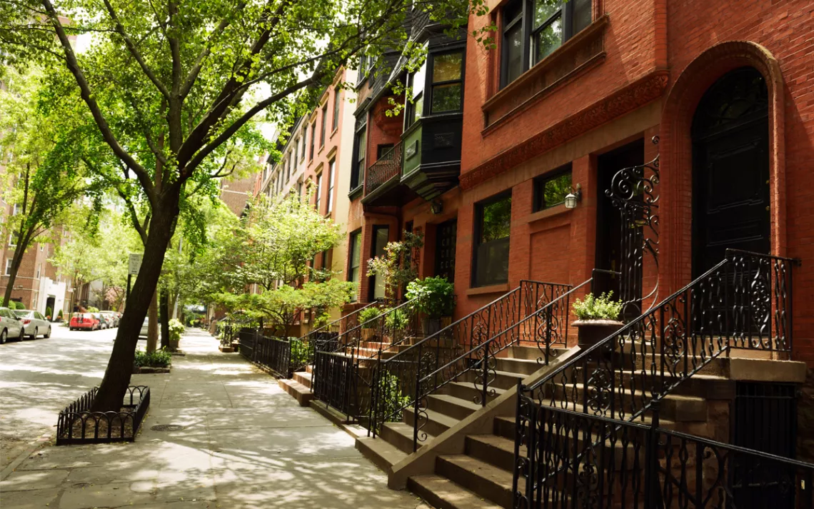 A row of brownstone homes with trees planted out front