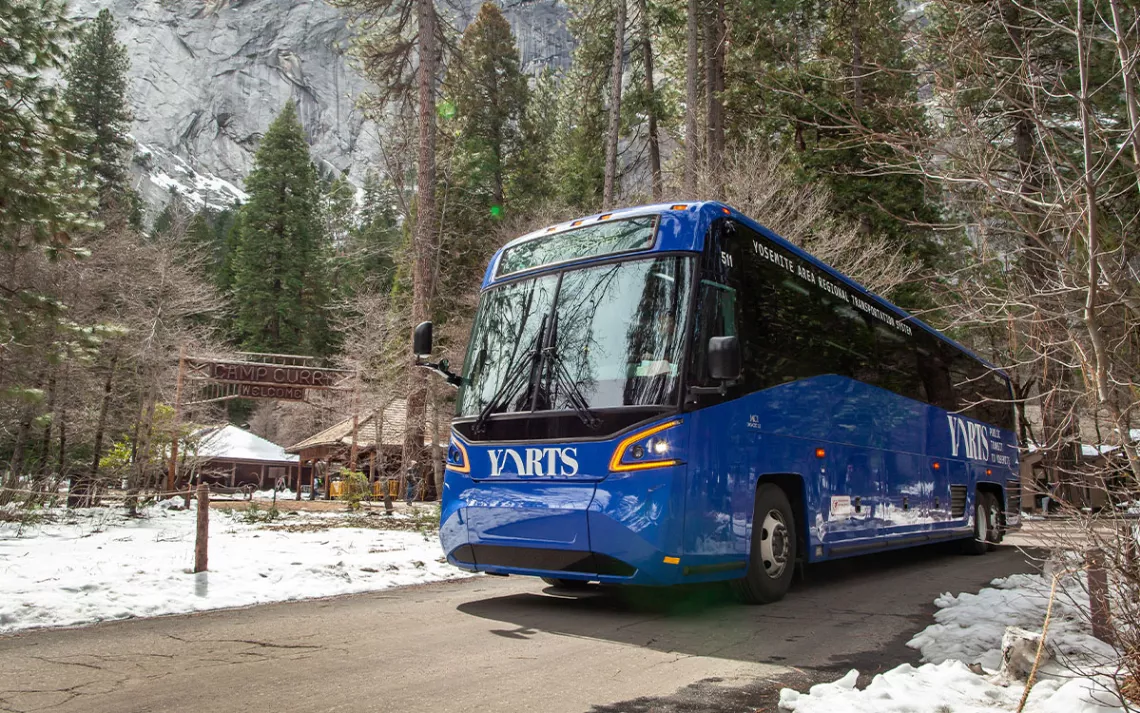 A YARTS public transit bus passes by Curry Village in Yosemite Valley after dropping off passengers.