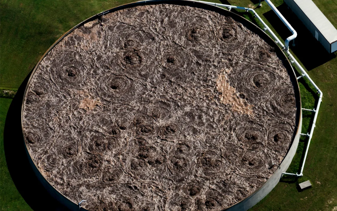 Aerial photo of a huge vat of brown "slurry" in a grassy field