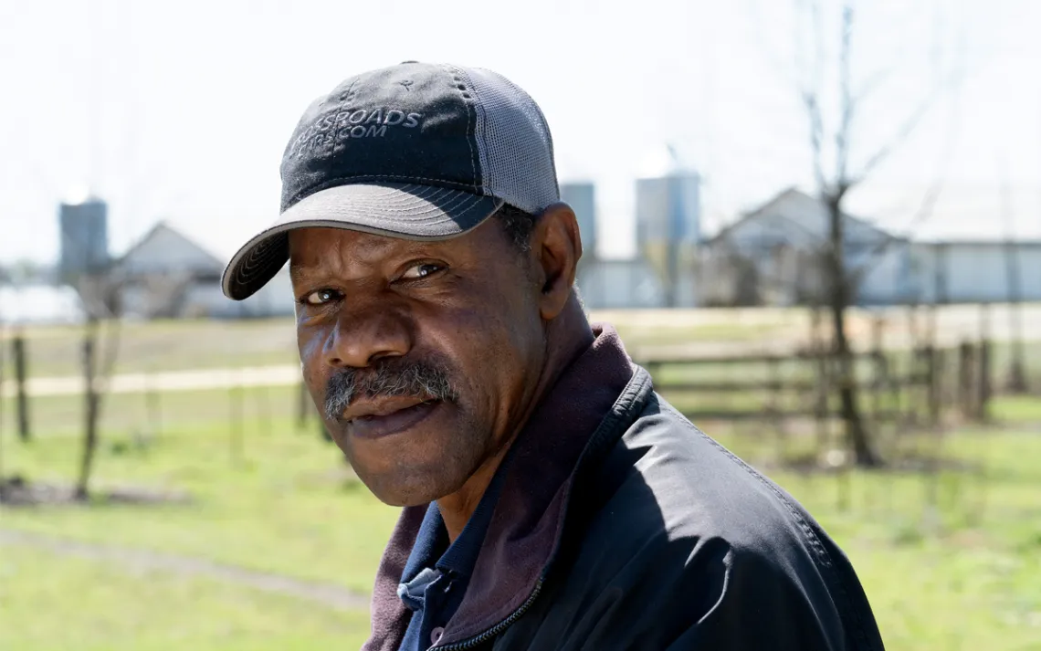 Rayford Bennett Sr. wears a baseball cap and stands in a field