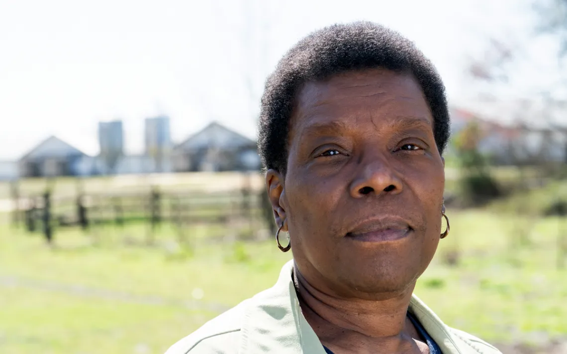 Sherri White-Williamson wears a light collared shirt and stands in a field