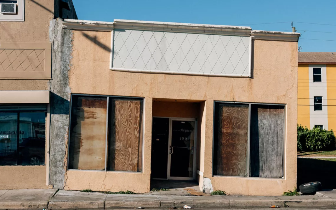A boarded-up, dilapidated beige building
