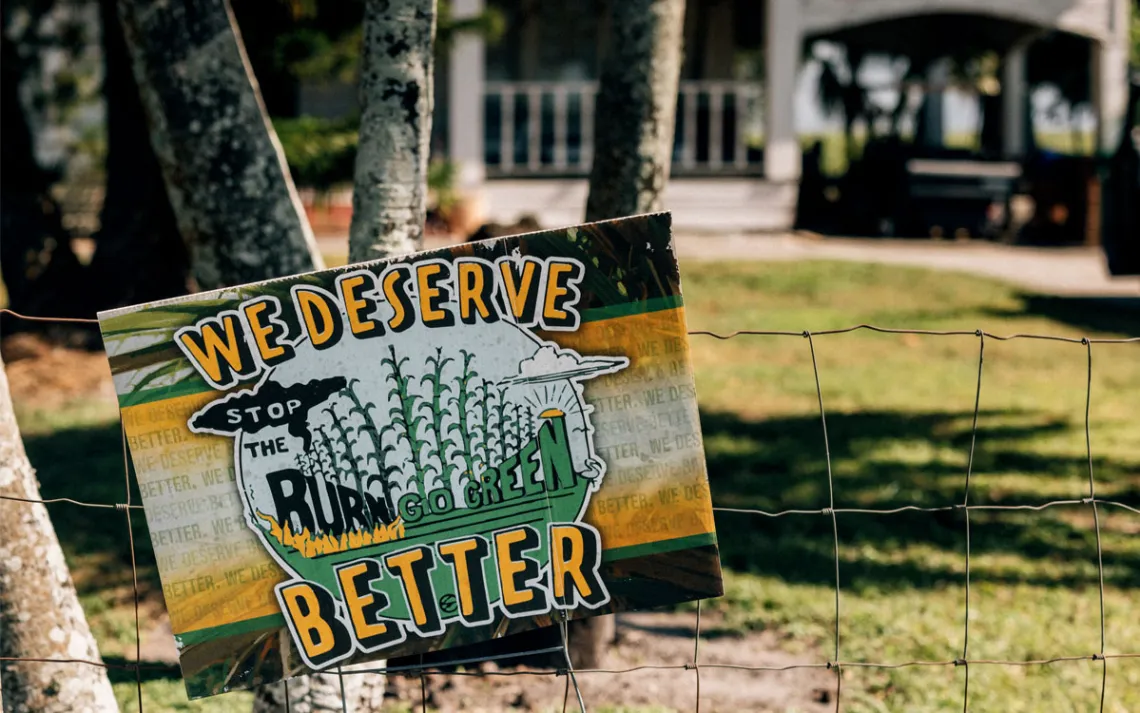 A yard sign reads "We Deserve Better, Stop the Burn."