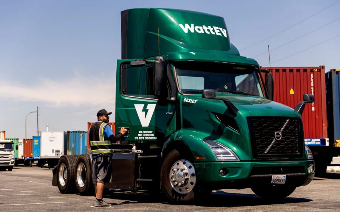 A man stands next to a green WattEV truck.