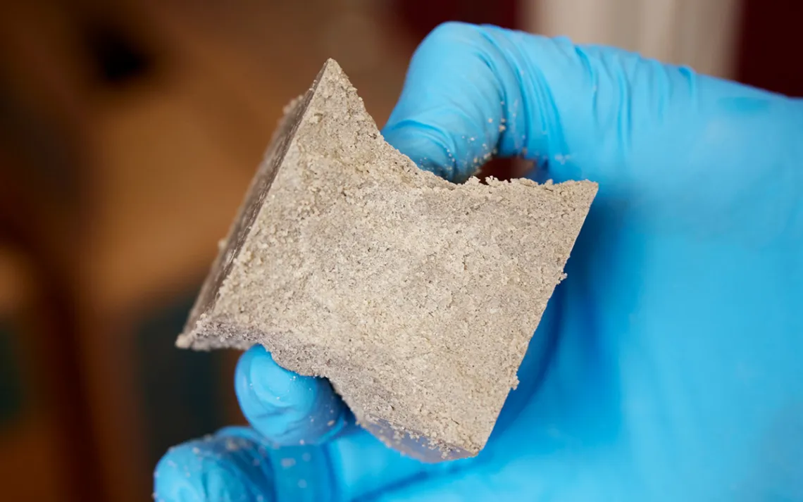 Close-up of a blue-gloved hand holding concrete