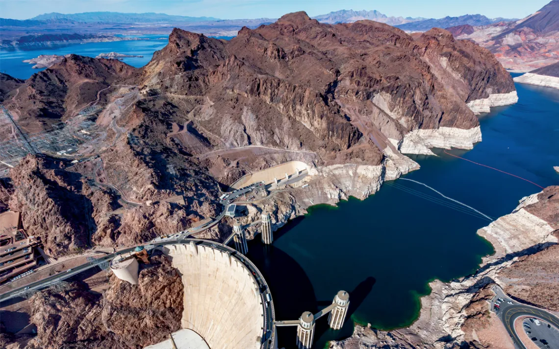 Aerial photo of Hoover Dam, with rocky mountains and Lake Mead in the background.