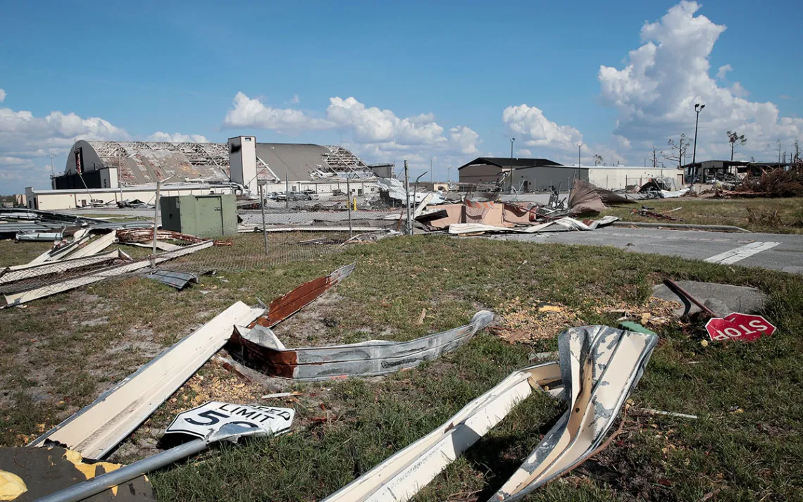 Tyndall Air Force Base is littered with debris after Hurricane Michael. A hangar's roof is missing tiles. Metal pieces, including a Stop sign, are on the ground.