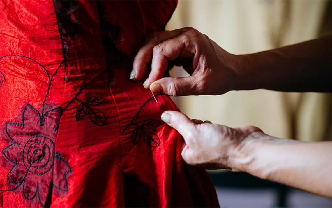 Close-up of woman's hands sewing with needle. 