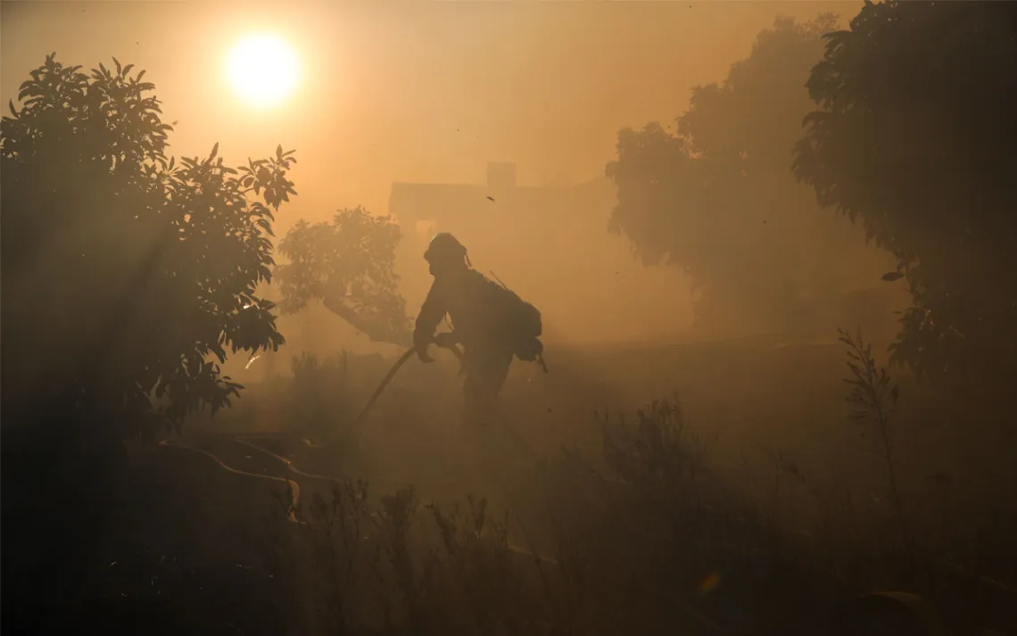 A firefighter pulls a water hose as a wildfires continues to burn Tuesday, Dec. 5, 2017, in Santa Paula, Calif