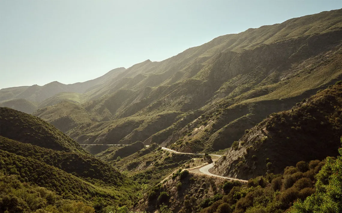 A winding road on the side of a forested slope