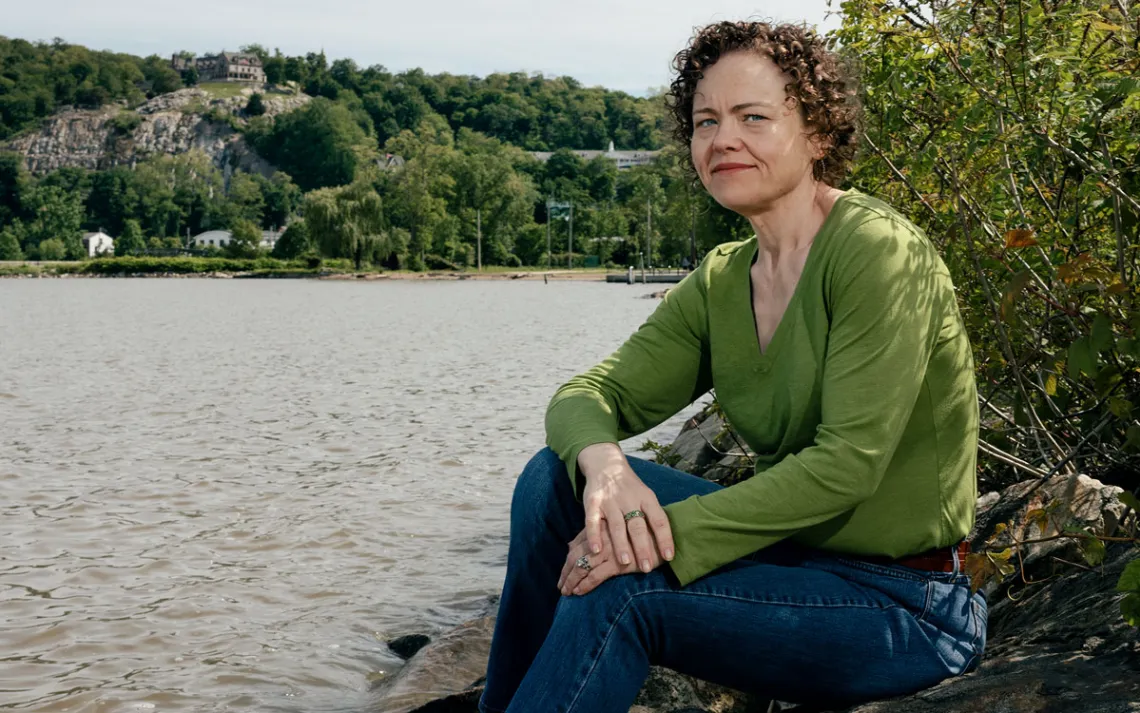 Courtney Williams is wearing a green shirt and sitting next to a river.