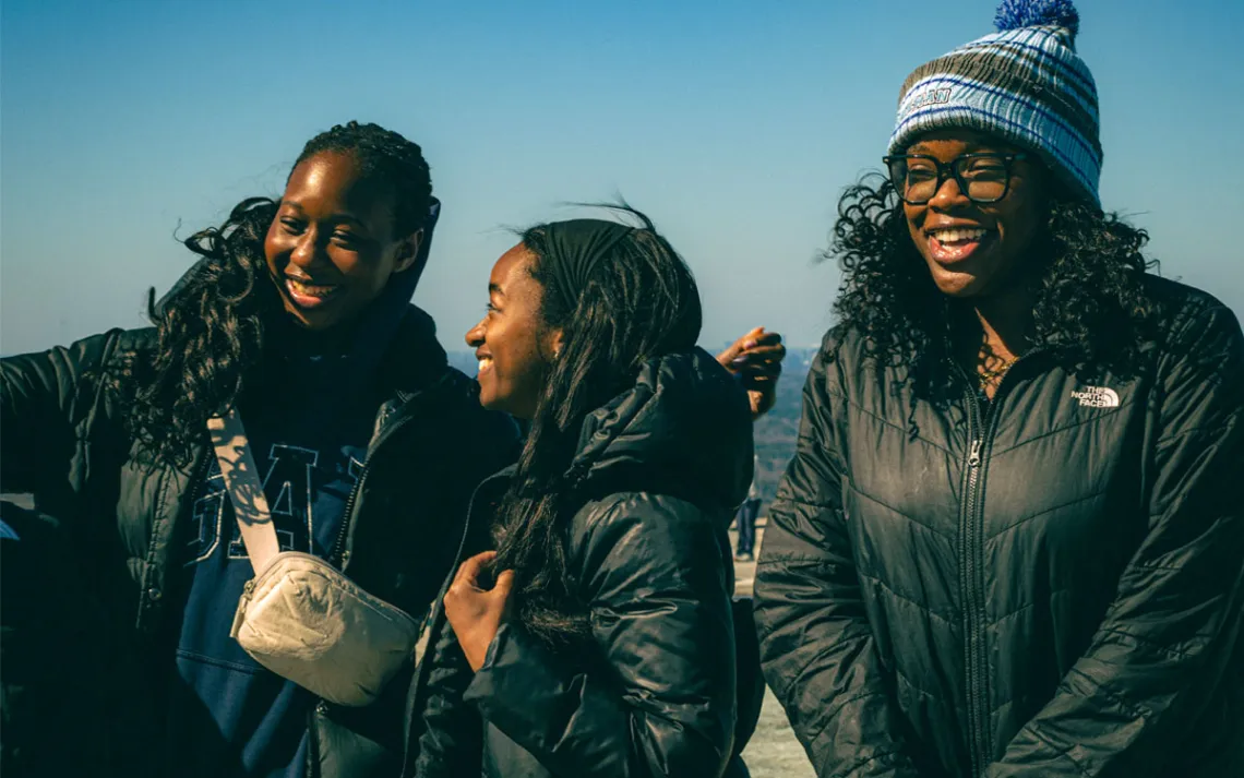 Three students huddled together atop Stone Mountain