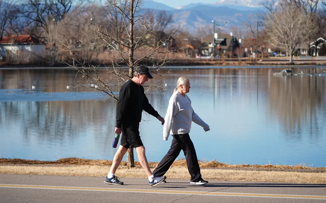Two people stroll through a snowless Denver park this past winter.