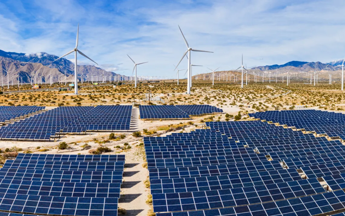 A field of solar panels and windmills in the desert.