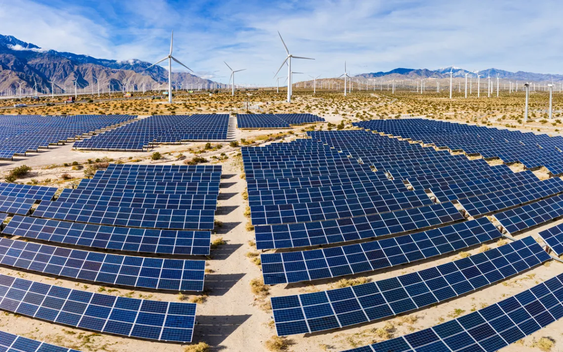 A field of solar panels and windmills in the desert.