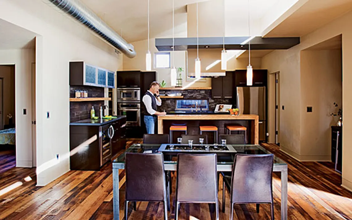 A "light shelf" reflects natural light from high windows deep into the house, showcasing reclaimed-lumber flooring.