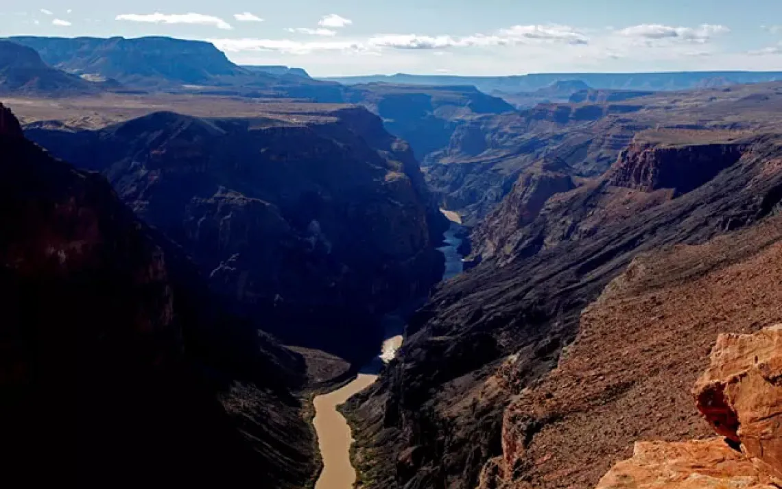 This photo from Toroweap looking west toward Whitmore Canyon shows Lava Falls on the north (right) canyon wall. A second lava falls can be seen in the distance. The white of Lava Falls rapids can be seen in the river.