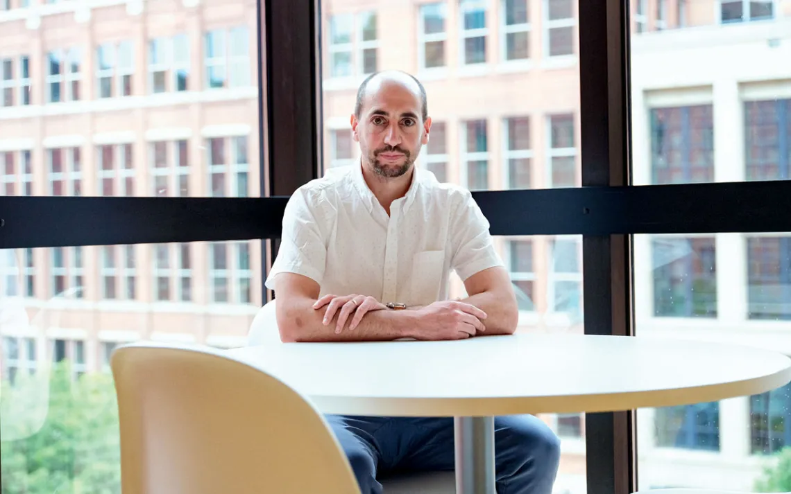 Joe Halso sits at a round table in an office building and looks directly at the camera.