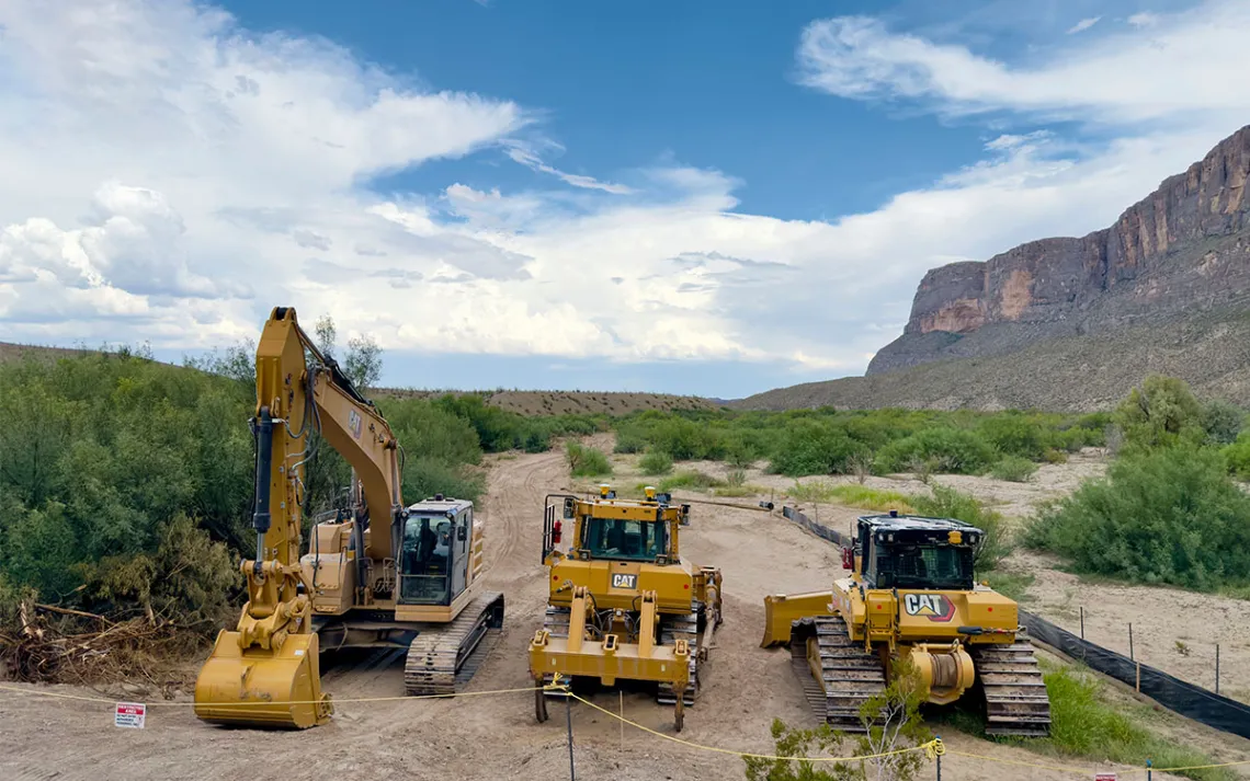 Construction trucks stand idyl along a section of the yet-to-build border wall.