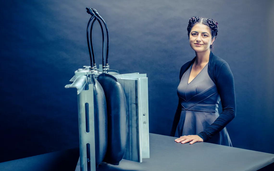 Leila Madrone, her hair in two tight buns, stands at a table with a solar device on it.