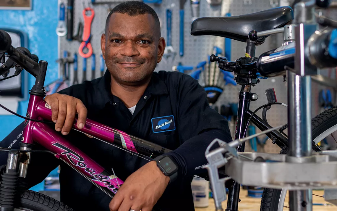 George Turner Jr. leans on a hot-pink and black Roadmaster bike and smiles at the camera.