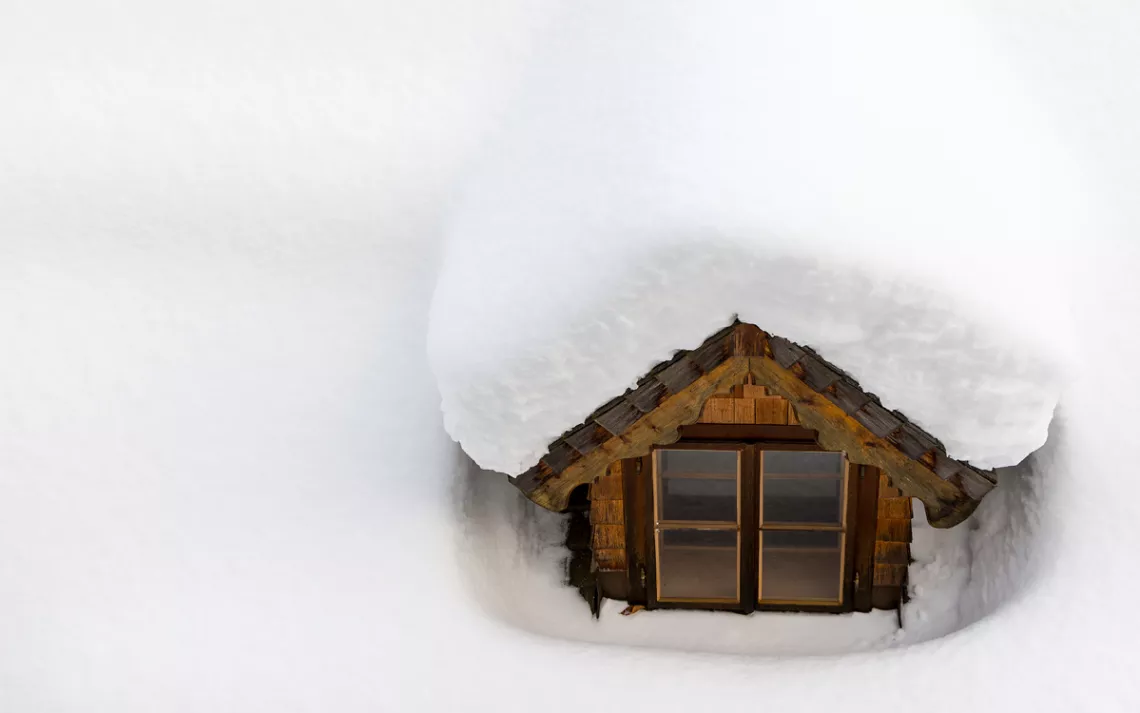 snow-covered roof with a small window peeking out of the snow cover