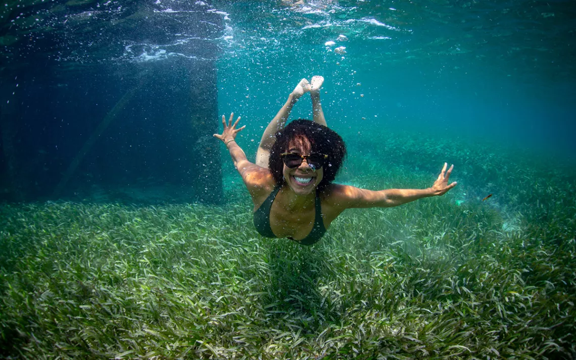 Marine biologist Ayana Elizabeth Johnson swimming underwater over a field of seagrass.