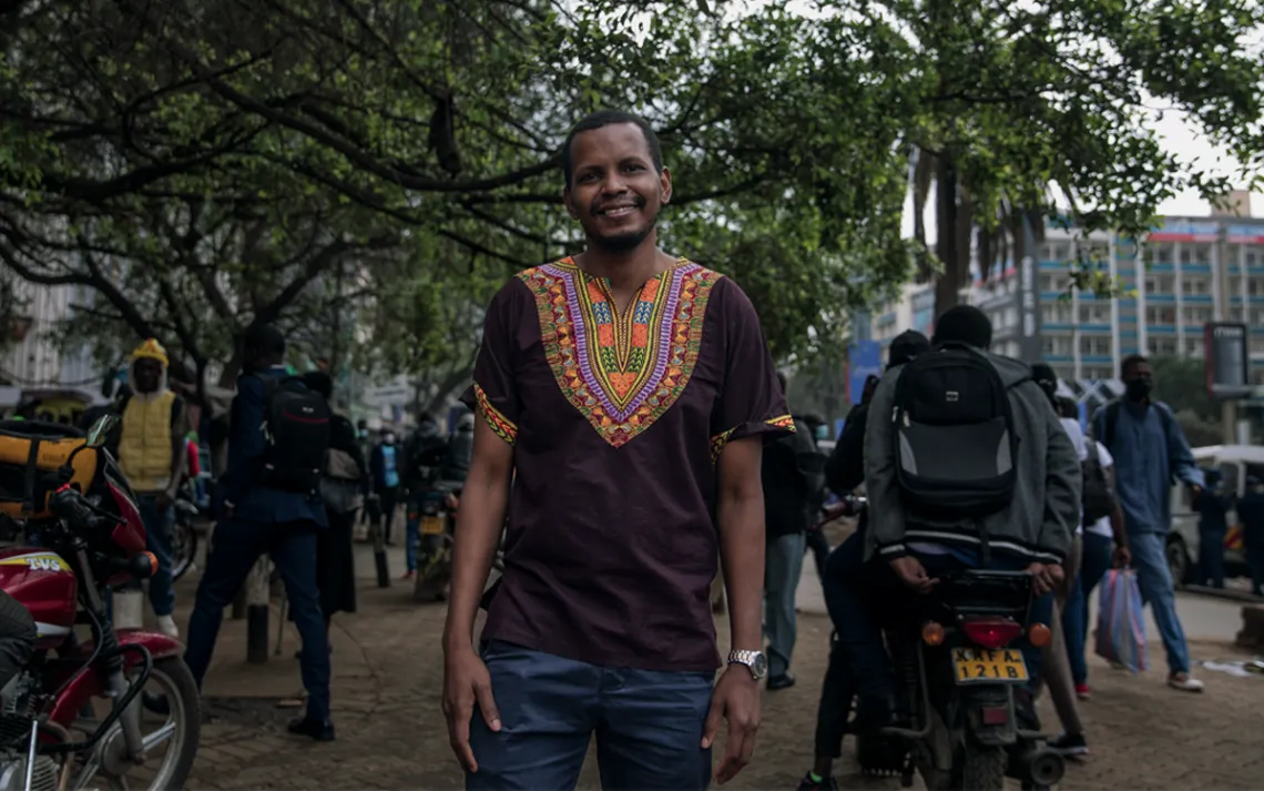 Omar Elmawi wears a colorful shirt and smiles at the camera.