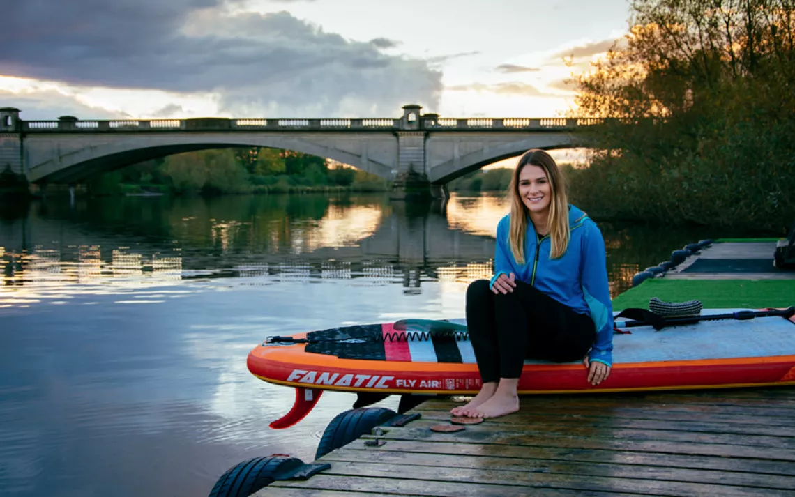 Lizzie Carr sits on a paddleboard on a dock next to the River Trent, Nottingham, UK.