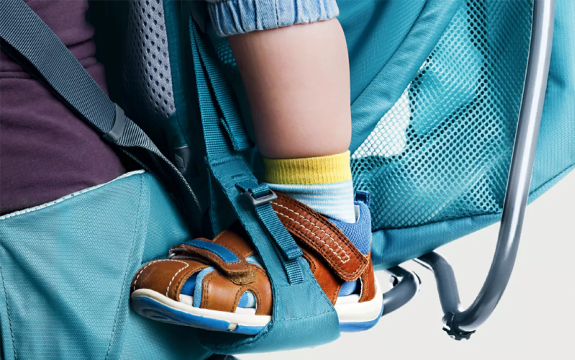 Turquoise Deuter Kid Comfort Active SL backpack with a toddler leg in a stirrup