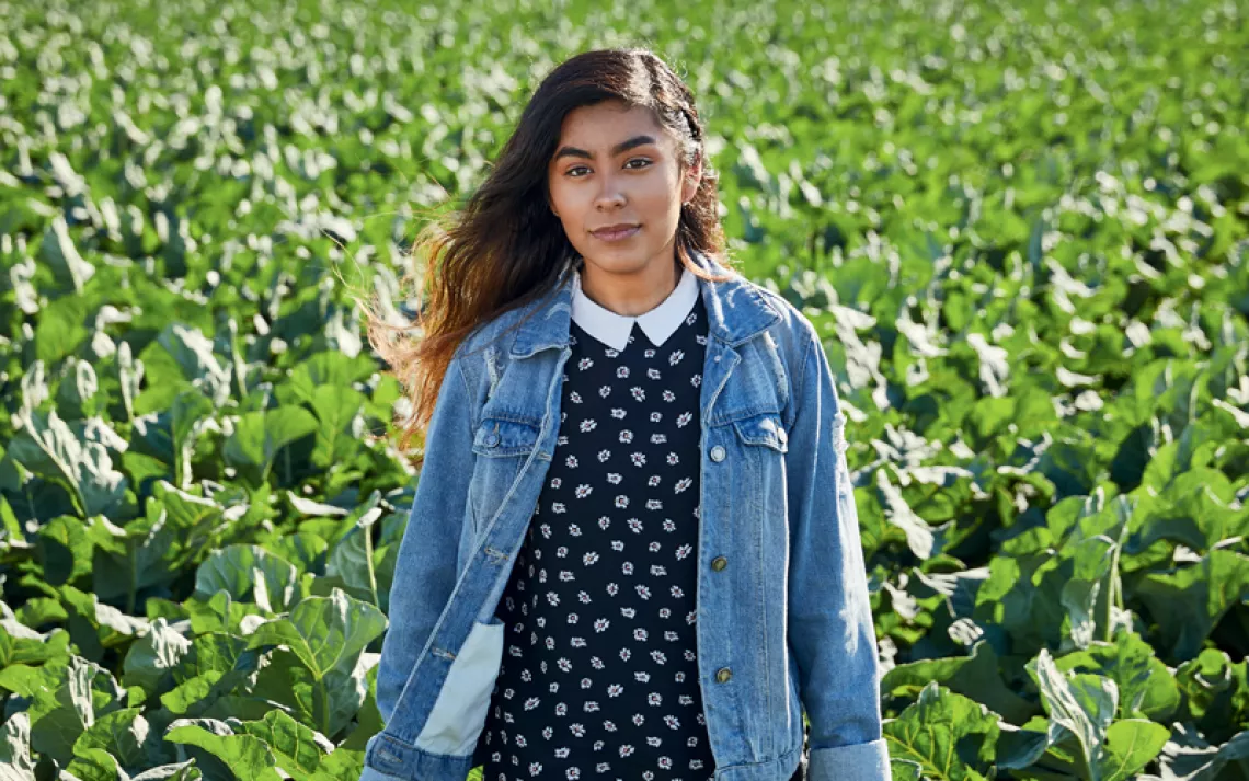 Magaly Santos stands in front of what appears to be a field of lettuce.