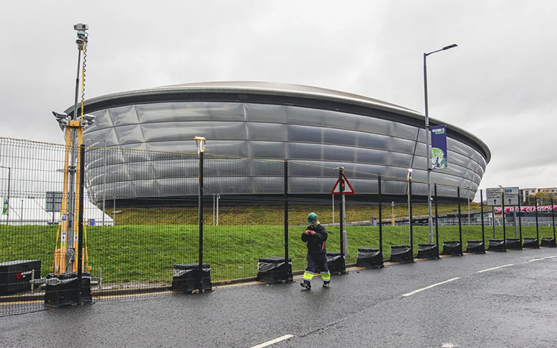 A futuristic silver looking building, like a canoe-shaped pillow of metal against green grass and a gray sky