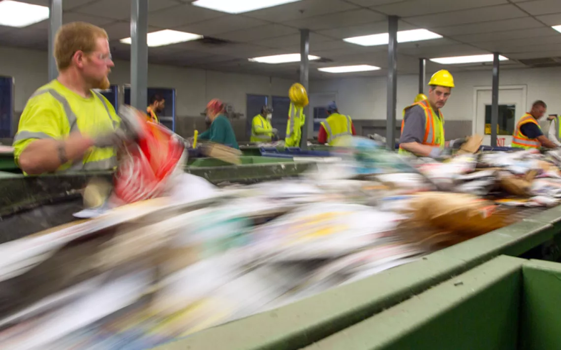 Workers in Portland Maine sort paper at Ecomaine recycling plant to remove contaminated recycling from the waste stream.