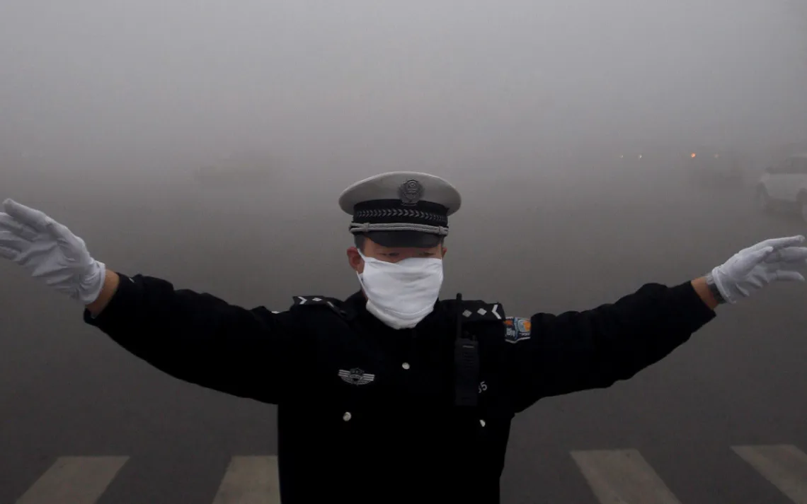 China, Harbin - October 21,  2013.A policewoman works in the heavy fog in Harbin in northeast China's Heilongjiang province Monday Oct. 21, 2013. Heavy fog shrouded northeastern China, disrupting traffic while pushing up air pollution in the cities. (Cred