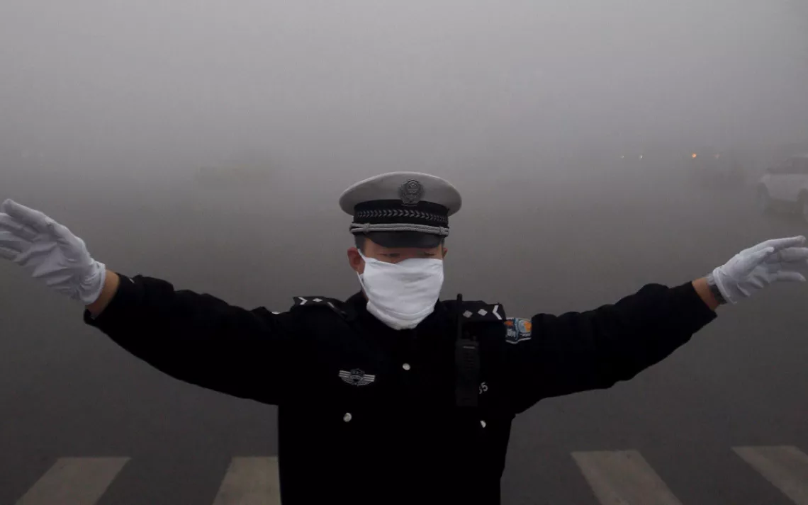 China, Harbin - October 21,  2013.A policewoman works in the heavy fog in Harbin in northeast China's Heilongjiang province Monday Oct. 21, 2013. Heavy fog shrouded northeastern China, disrupting traffic while pushing up air pollution in the cities. (Cred