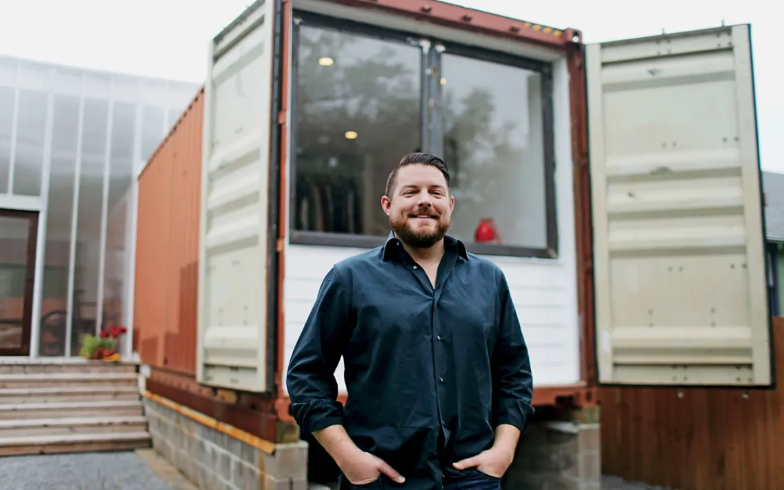Seth Rodewald-Bates stands in front of his upcycled storm shutters.