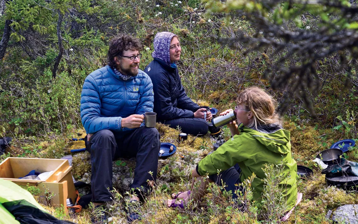 Jon Pratt, Kim Mihell, and Ginny Marshall sip warm drinks while waiting for the wind to die down.