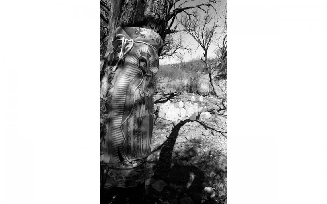 Somewhere in the desert wilderness of Santa Cruz County, Arizona, someone has left jugs of water for people crossing the border. A poster of the Virgin of Guadalupe watches over the water cache. | Photo by Alejandra Platt-Torres 