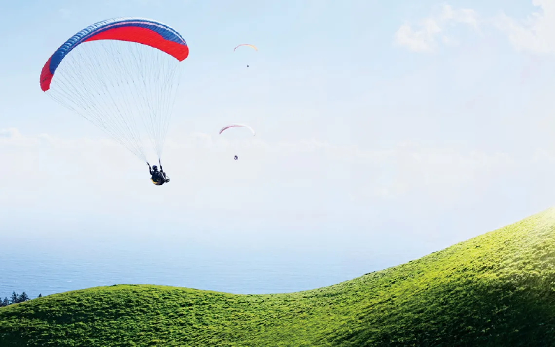 Three paragliders descend along the curvy flanks of Mt. Tamalpais in Marin County, California, overlooking the Pacific Ocean. 