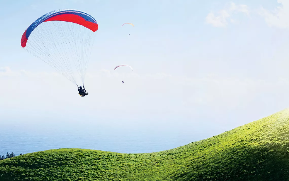 Three paragliders descend along the curvy flanks of Mt. Tamalpais in Marin County, California, overlooking the Pacific Ocean. 