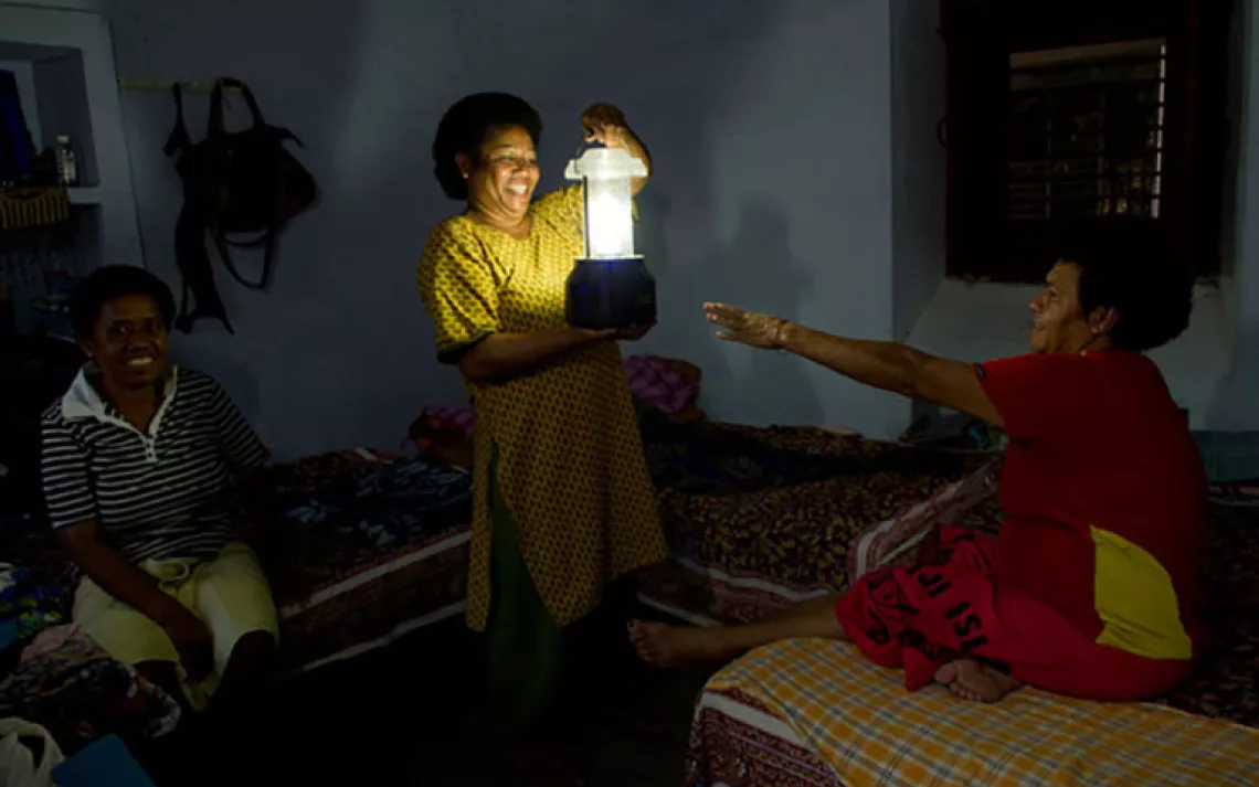 Titilia Somica holds a solar lantern made at Barefoot College in the darkness of the room she shares with fellow Fijians Marica Caginitoba (left) and Vulori Susu.