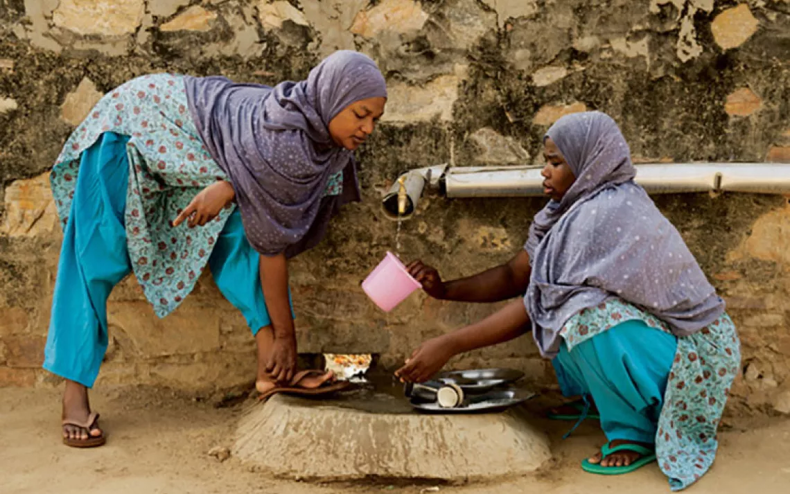 Zanzibaris Mize Juma (left) and Patima Othmani wash dishes with solar-heated water.