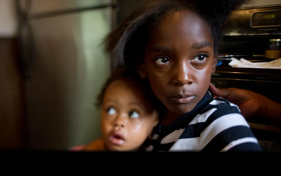 Marianna Hildreth, 7, holds her cousin Mariyah McGhee, 1, who has asthma, in their grandmother's kitchen in River Rouge, Michigan. | Ami Vitale/Panos Pictures