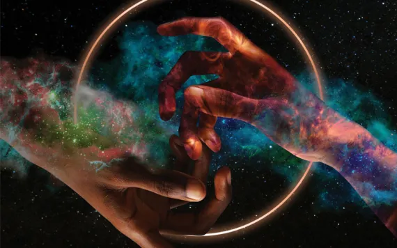 Photo illustration shows two hands coming together in front of a solar eclipse and a galaxy.