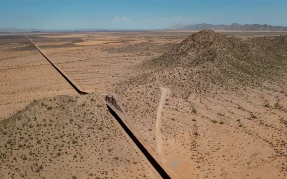 Aerial photo of a large stretch of border wall cutting through scrubby desert landscape.