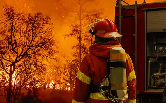 Firefighter extinguishing wildfire with fire truck. Photo byToa55 | iStock