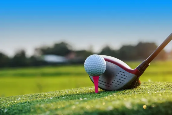 golf club in front of a golf ball on a tee