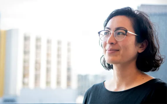 Rose Abramoff wears glasses and a black top and smiles, looking off to her right