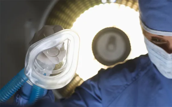 A doctor holds a nebulizer mask in an operating room.